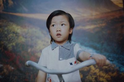 a young girl is holding a bike in front of a picture