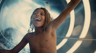 a boy with dreadlocks standing in front of a wall