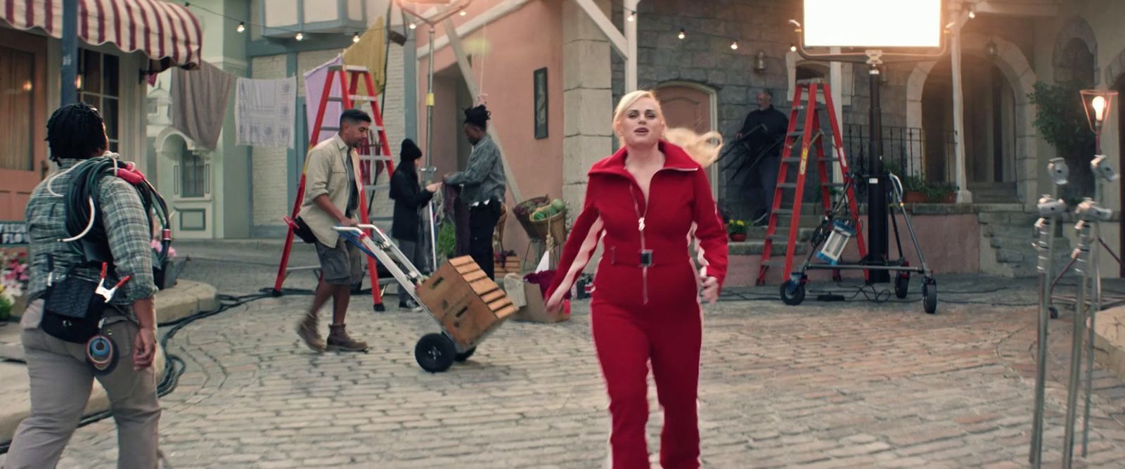 a woman in a red jumpsuit walking down a street