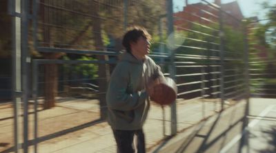 a man holding a basketball while standing next to a fence