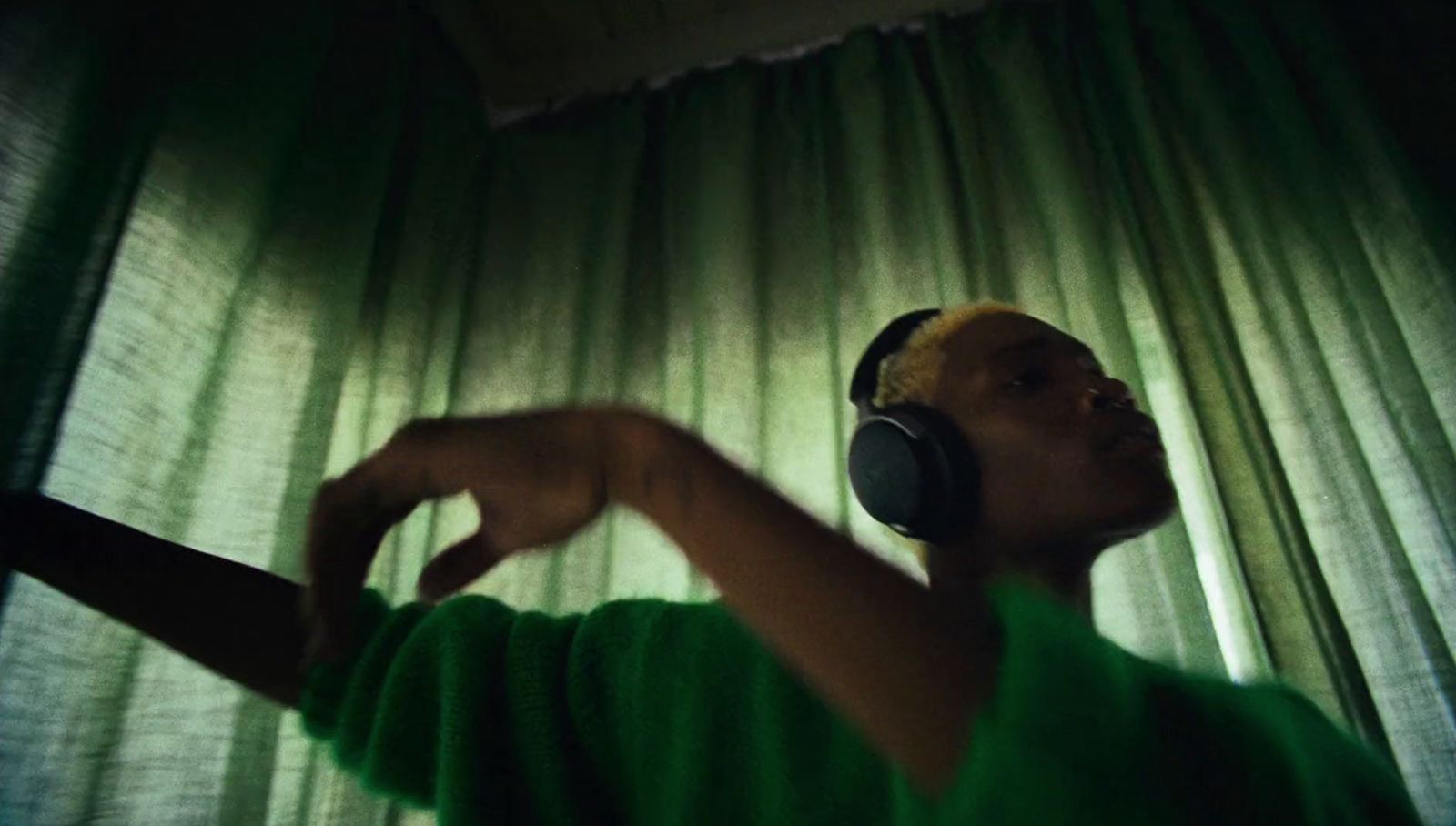 a man with headphones on in front of a curtain