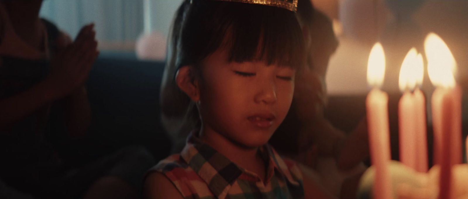 a little girl wearing a crown standing in front of a cake with lit candles