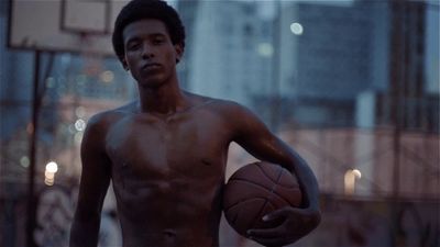 a shirtless man holding a basketball in a city