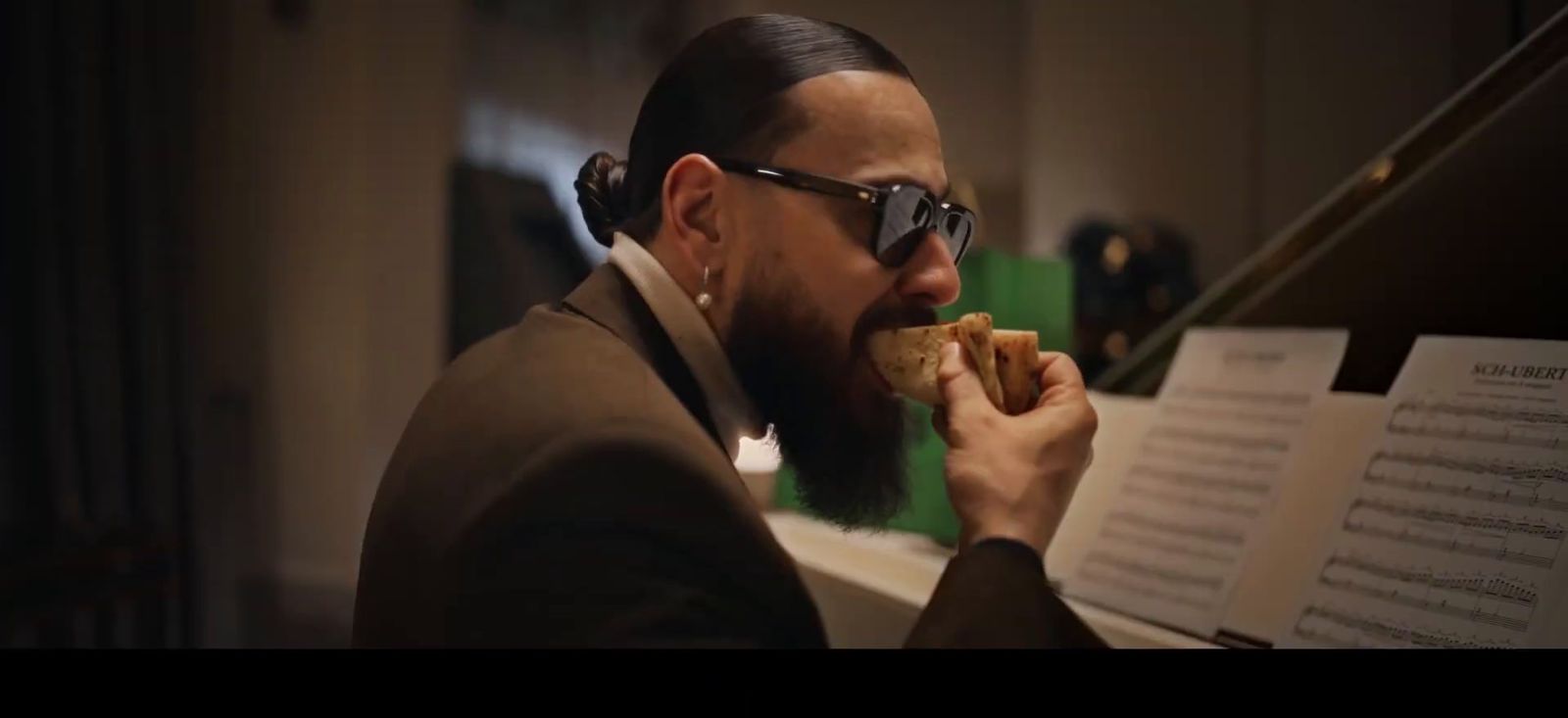 a man with a beard eating a sandwich