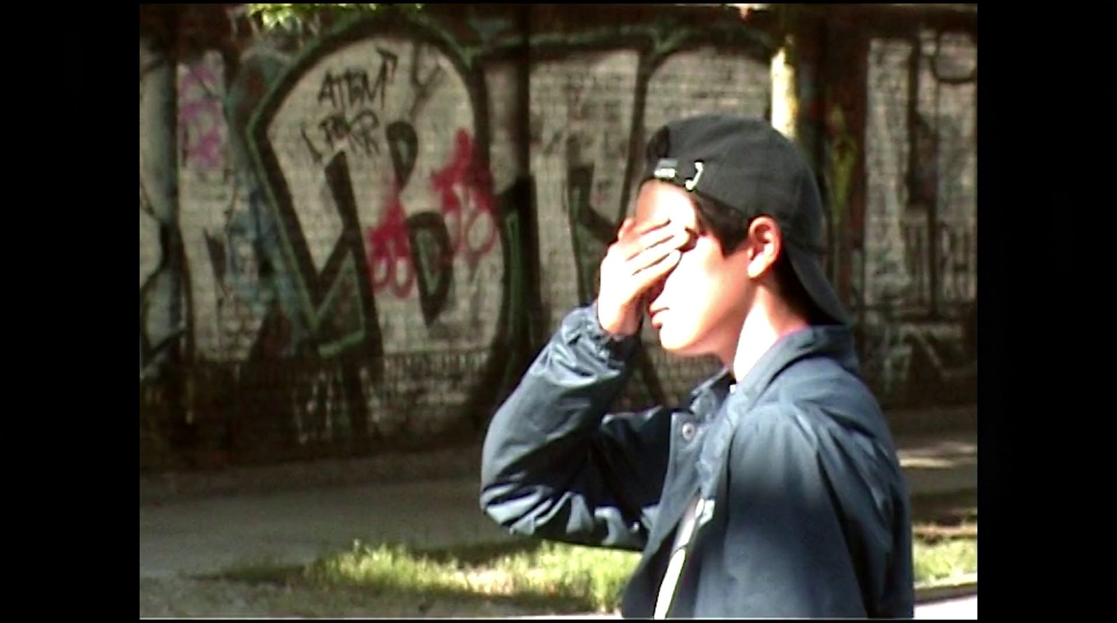 a man standing in front of a wall with graffiti on it