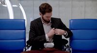 a man sitting in a chair tying his tie