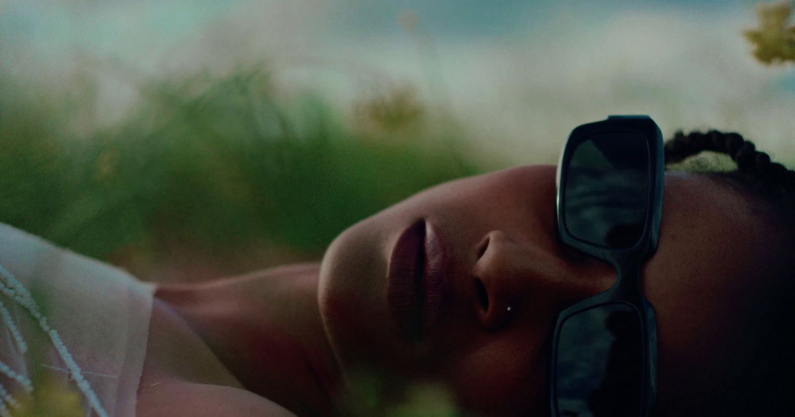 a woman wearing sunglasses laying in a field