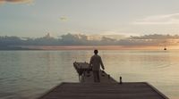 a man standing on a dock watching the sunset