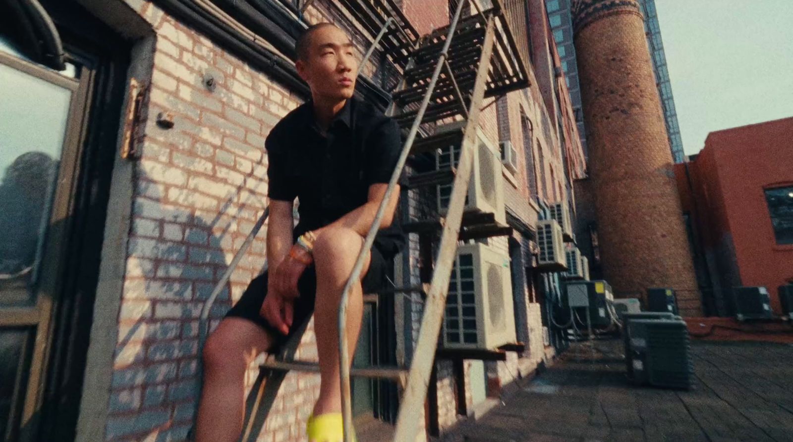 a man sitting on top of a ladder next to a building