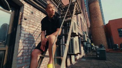 a man sitting on top of a ladder next to a building