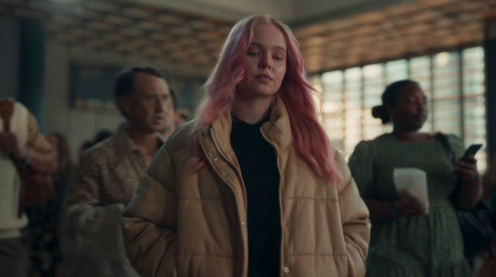 a woman with pink hair standing in front of a group of people