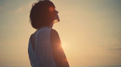 a woman standing on a beach at sunset