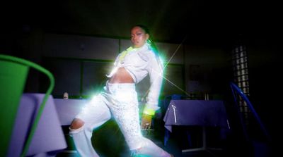 a man dressed in white dancing in a dark room