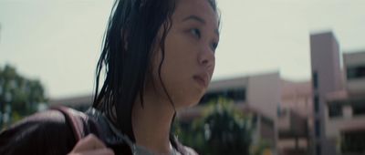 a woman with black hair standing in front of a building