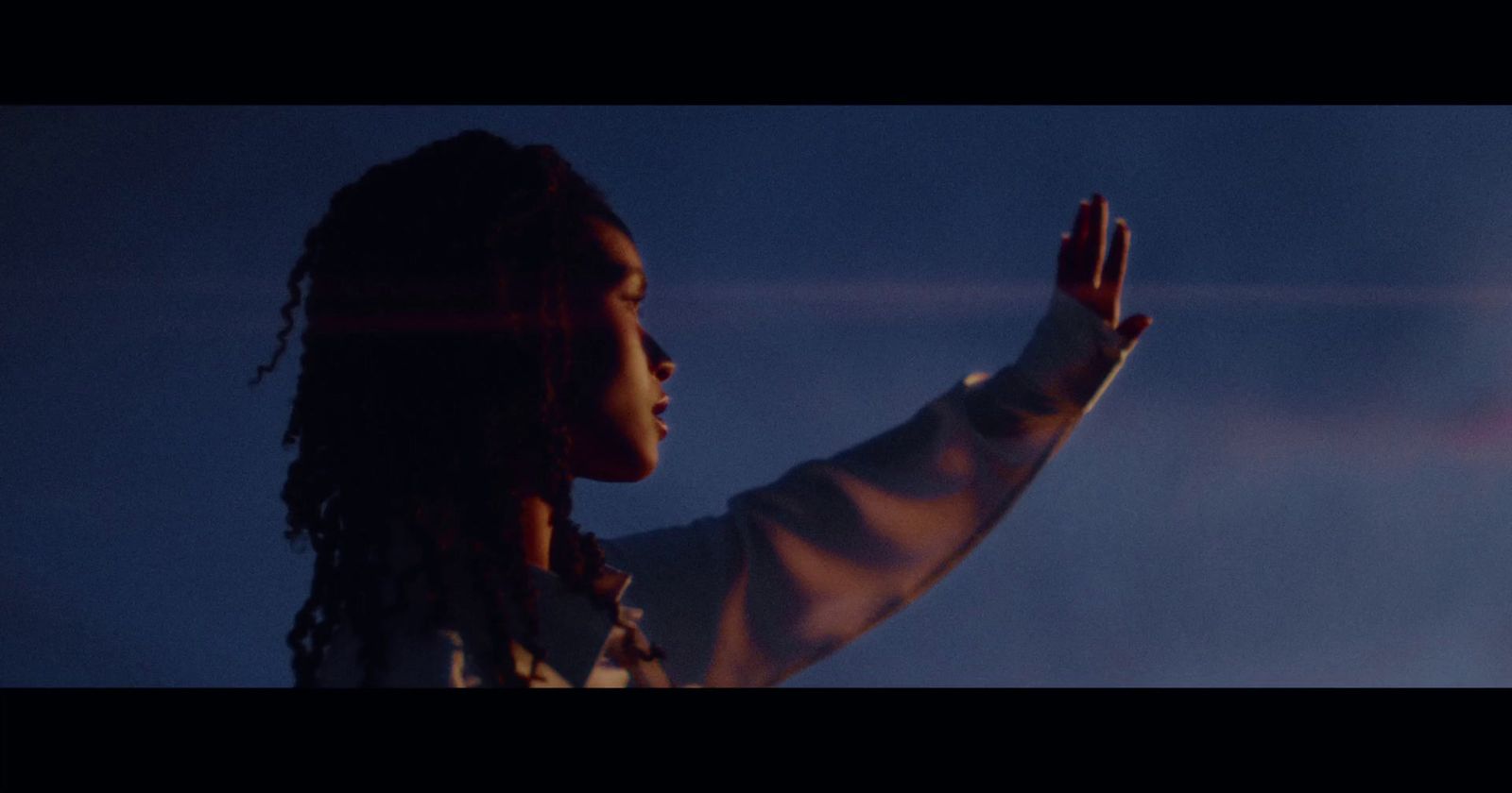 a woman with dreadlocks holding her hand up in the air