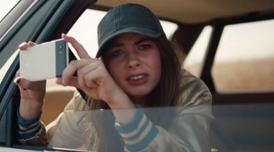 a woman sitting in a car holding up a camera