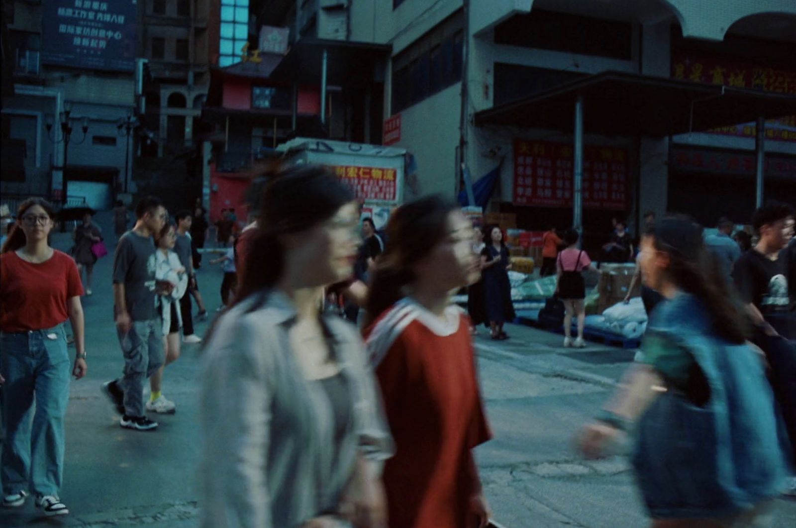 a group of people walking down a street next to tall buildings