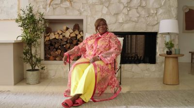 a woman sitting in a chair in front of a fire place