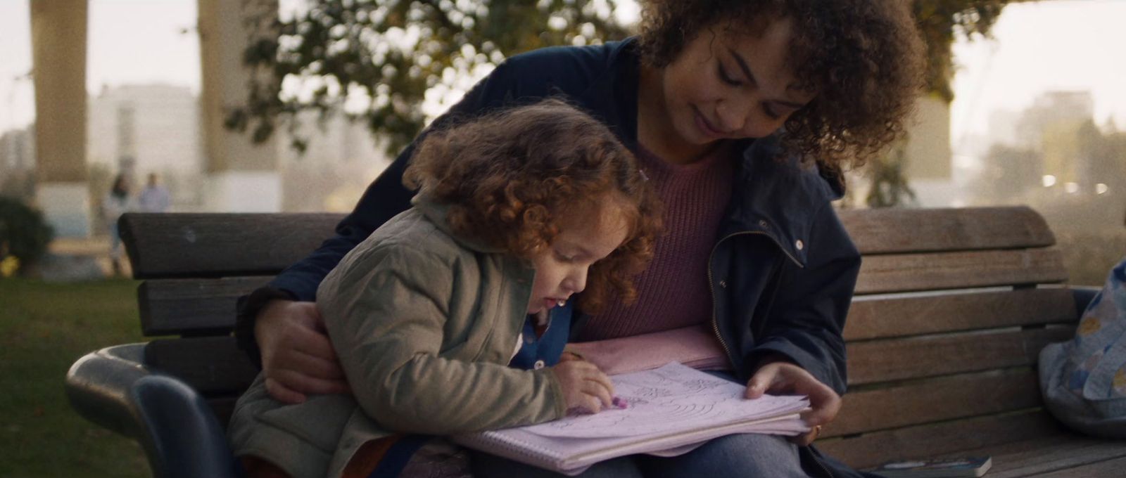 a woman sitting on a bench with a little girl