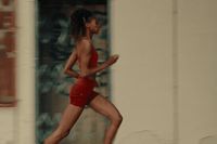 a woman in a red swimsuit running down a street