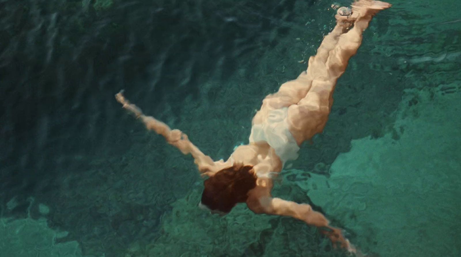 a man swimming in the ocean with his shirt off