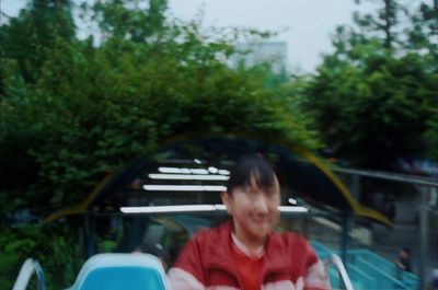 a woman sitting on a blue chair in a park