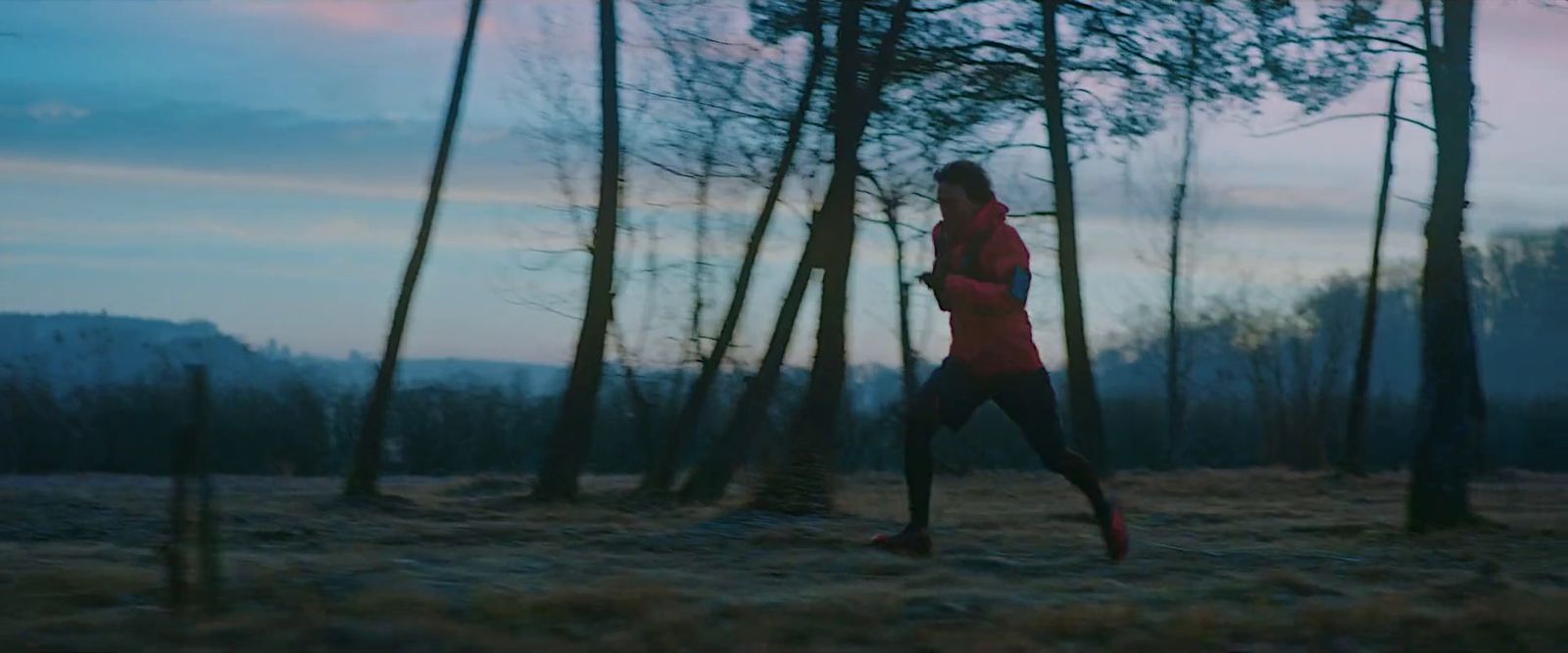 a woman running through a forest at dusk