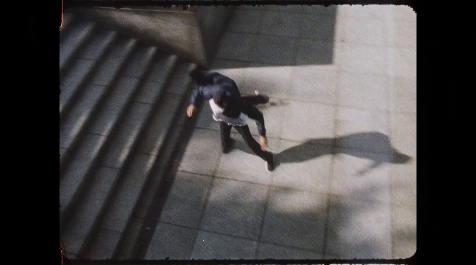 a man walking down a sidewalk next to a metal hand rail