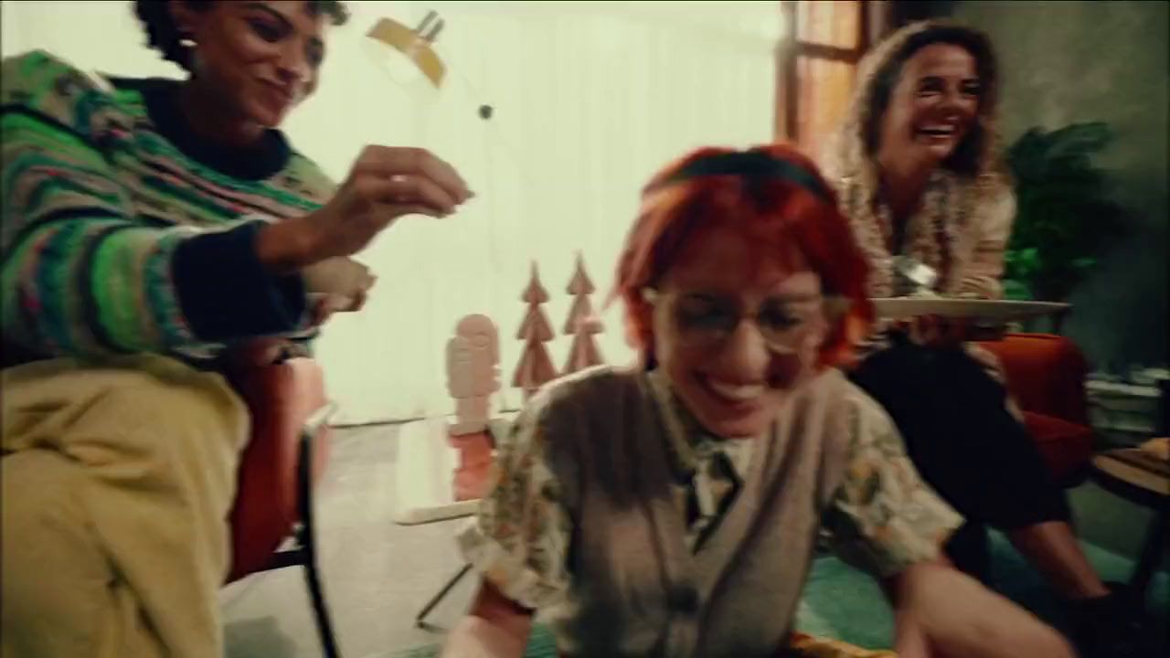 a woman with red hair and glasses cutting a cake