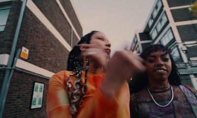 two women standing next to each other in front of a building