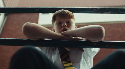 a young boy wearing a tie sitting on a metal rail