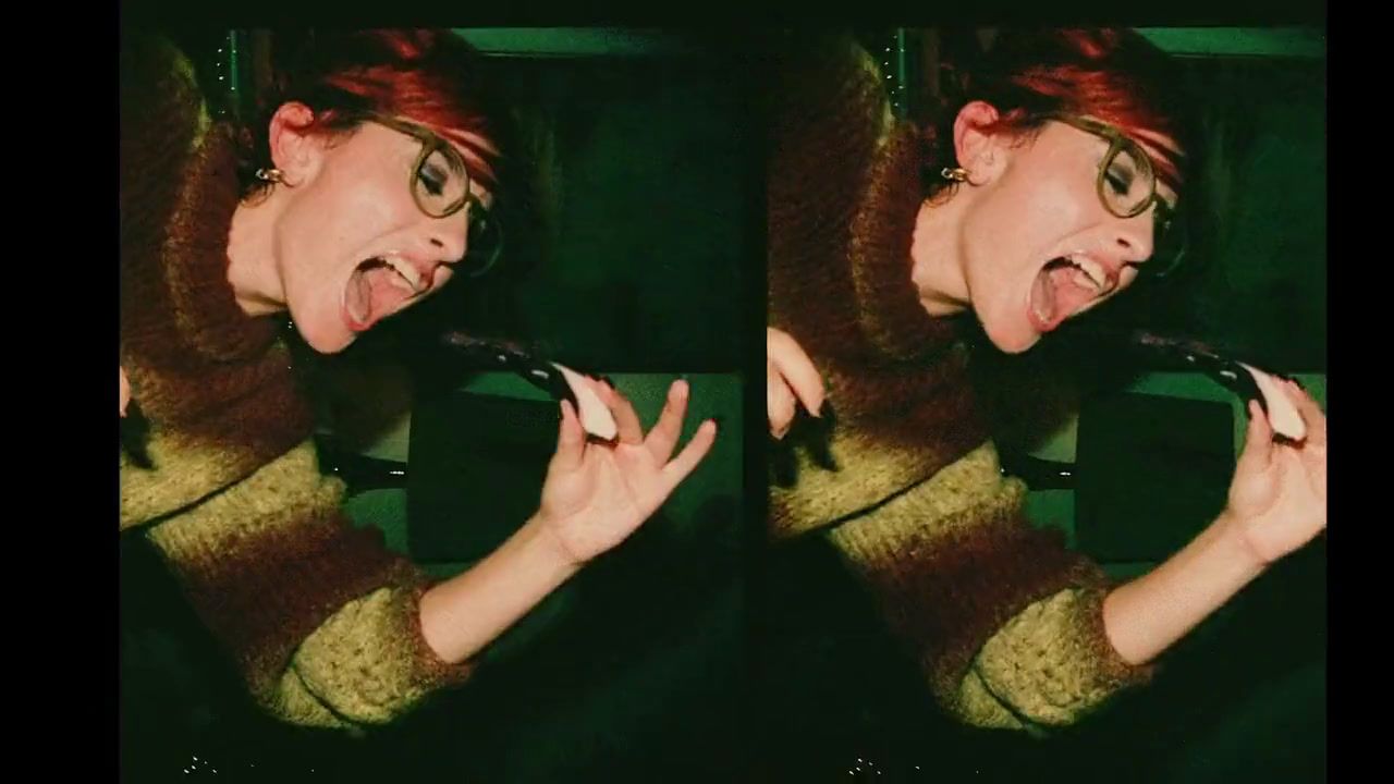 a woman with red hair and glasses holding a black object