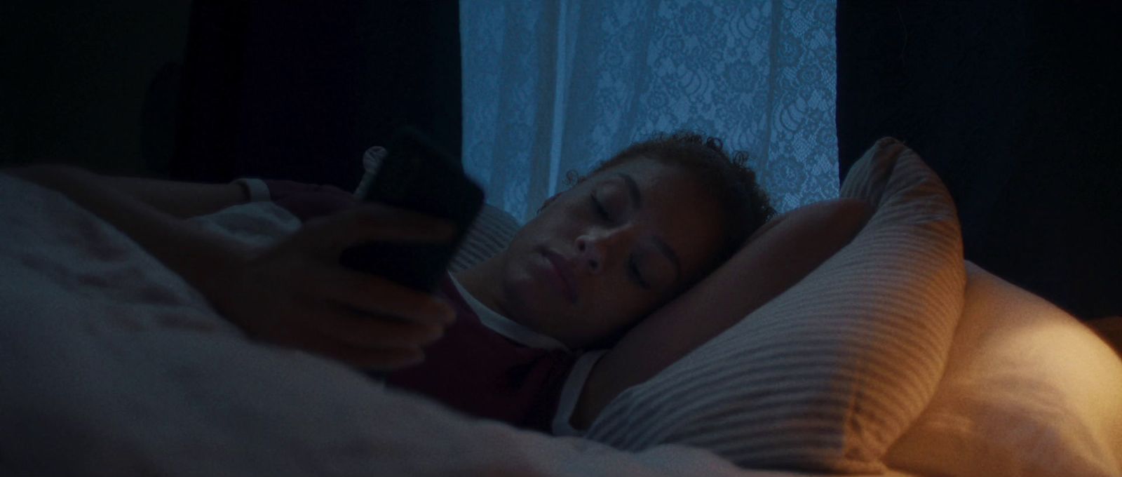 a woman laying in bed holding a remote control