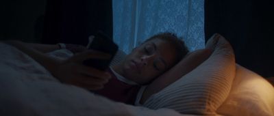 a woman laying in bed holding a remote control