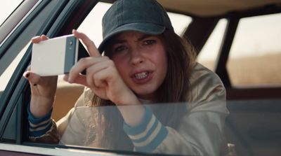 a woman in a car taking a picture with her cell phone