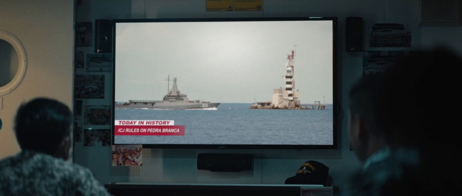 a man watching a ship in the ocean on a flat screen tv