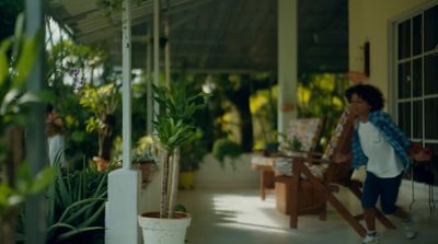 a woman walking down a porch next to potted plants