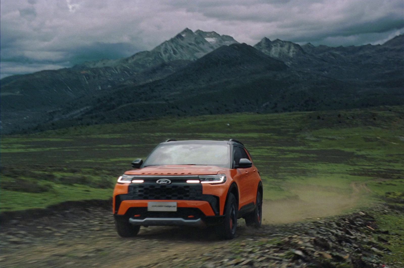 an orange suv driving down a dirt road