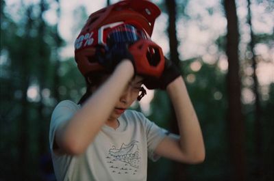 a young boy wearing a red helmet in the woods