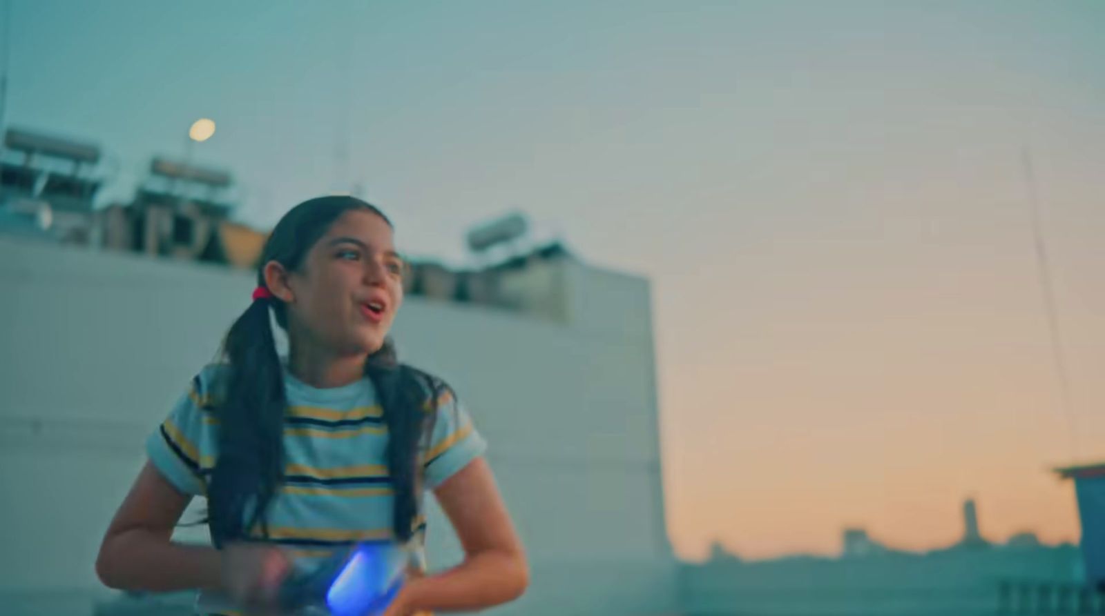 a young girl holding a blue frisbee in front of a building