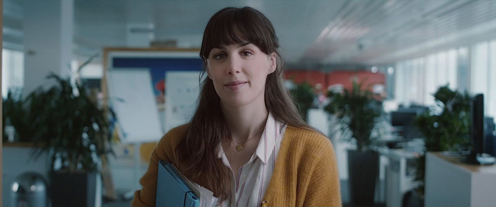 a woman standing in an office holding a folder