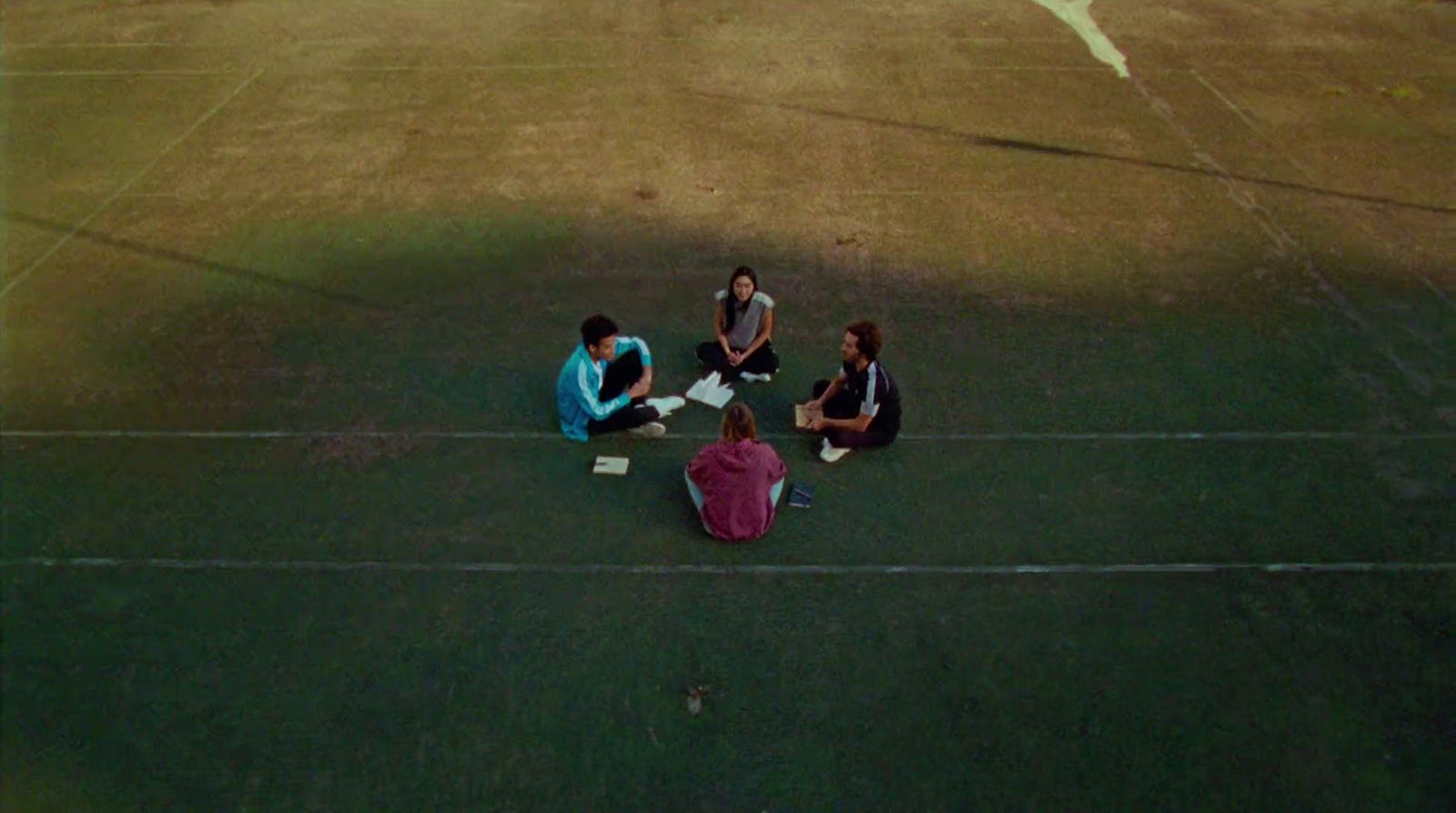 a group of people sitting on top of a grass covered field