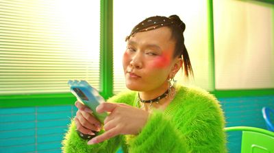 a woman in a green fuzzy sweater looking at a cell phone