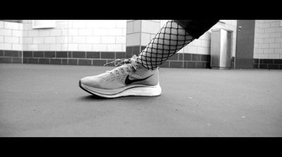 a black and white photo of a person's legs and shoes