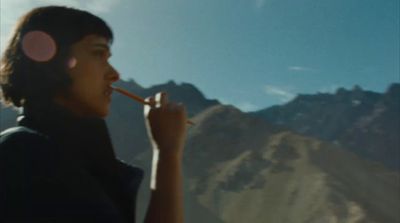 a man with a pencil in his mouth and mountains in the background