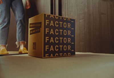 a person standing next to a box that says factor factor factor factor factor factor factor