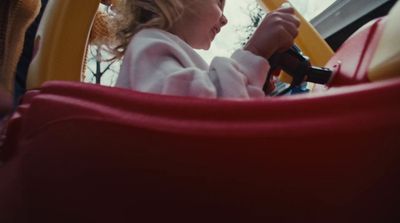 a little girl sitting in a toy car