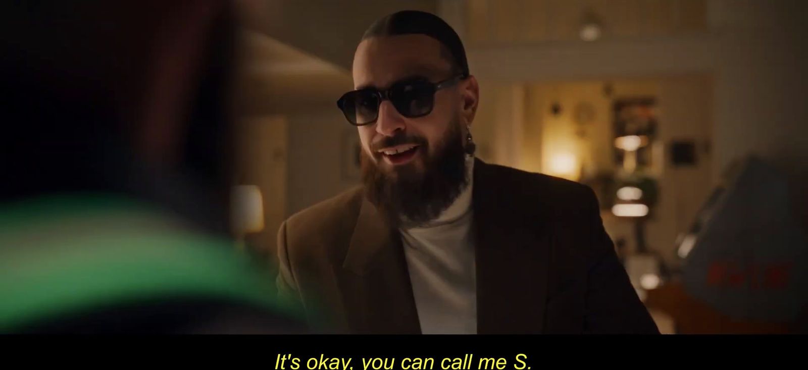 a man with a beard wearing sunglasses talking to another man