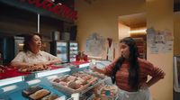 a woman standing in front of a counter filled with pastries