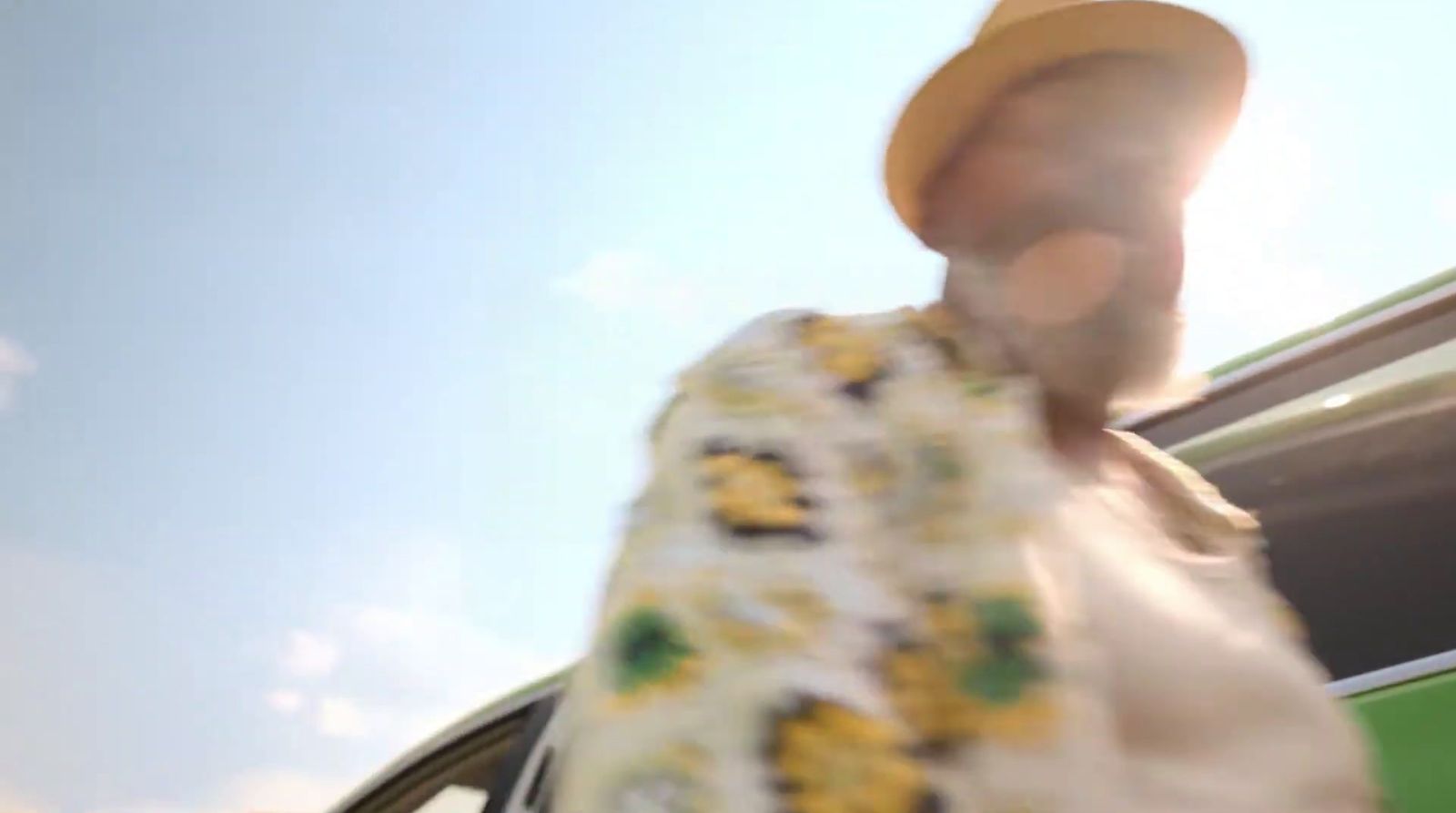 a man with a hat and a tie walking towards a car